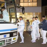 Local government officials of Miyazaki Prefecture get on a bus Tuesday evening to conduct a mass culling of chickens at a farm in the Kijo district where an avian flu virus was detected. | KYODO
