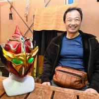 Courage Force Inc. President Tamotsu Ebina poses with the masks of the Japanese Miraigar (left) and Thai Miraigar on Dec. 7 in Nikaho, Akita Prefecture. | KYODO