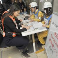 Employees of Mori Building Co. take part in a disaster drill held in three languages at the Roppongi Hills commercial complex in Tokyo on Tuesday. | YOSHIAKI MIURA