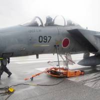 An Air Self-Defense Force F-15 fighter jet sits on the runway at Naha Airport after developing trouble in its front-landing gear Monday. | ASDF/ VIA KYODO