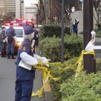 Police investigate outside the industry ministry in Tokyo where a 78-year-old man allegedly started a shrubbery fire on Monday. KYODO | AP
