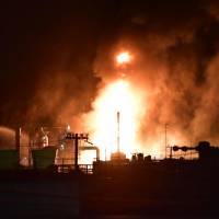 Flames and smoke are seen Sunday night at a TonenGeneral Sekiyu K.K. refinery in the city of Arida, Wakayama Prefecture, after a fire broke out during the afternoon. | KYODO