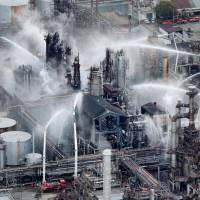 Firefighters spray water on a fire at the TonenGeneral Sekiyu K.K. refinery in Arida, Wakayama Prefecture on Monday after a blaze erupted there a day earlier. | KYODO
