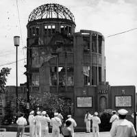 This photograph, taken on Sept. 8, 1955, just over 10 years after the bombing of Hiroshima, shows U.S. Navy sailors looking at what is now called the A-Bomb Dome. | HIROSHIMA PEACE MEMORIAL MUSEUM / VIA KYODO