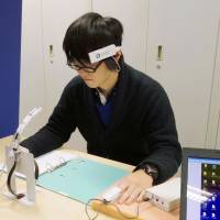 A student at Kagawa University participates in an experiment in which his brain and heart data are scanned while he smells Japanese incense. | KYODO