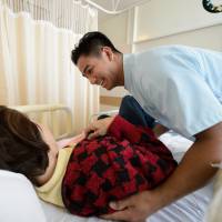 Filipino care worker John Denmark Pineda assists an elderly resident at Eisei hospital in Tokyo on Dec. 6. | BLOOMBERG