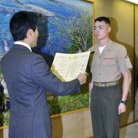 Yuto Yoshida, mayor of Yokosuka, Kanagawa Prefecture, awards a certificate of gratitude to a U.S. serviceman Monday. | KYODO