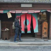 Crossing the threshold: A woman walks through hanging curtains to enter Daigokuden, a sweets shop in Kyoto. | J.J. O\'DONOGHUE