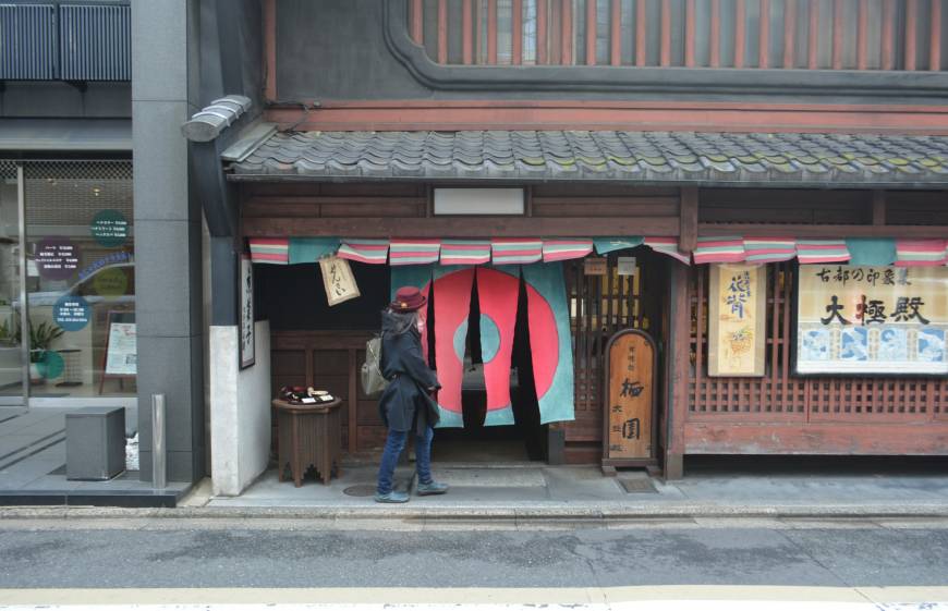 Crossing the threshold: A woman walks through hanging curtains to enter Daigokuden, a sweets shop in Kyoto.