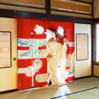 A woman dressed in a bridal outfit enters a room a through a noren at the Bridal Curtain Museum in Nanao, Ishikawa Prefecture. | COURTESY OF THE BRIDAL CURTAIN MUSEUM