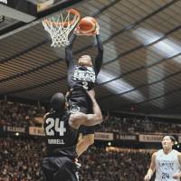 B. Black guard Yuki Togashi gets an assist from teammate Justin Burrell as he dunks during the B. League All-Star Game at Yoyogi National Gymnasium on Sunday. B. Black defeated B. White 117-95. | YOSHIAKI MIURA