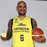 New Sunrockers center Robert Sacre holds a basketball and a cup of shaved ice as he poses for photos during a news conference on Thursday in Shibuya. | KAZ NAGATSUKA