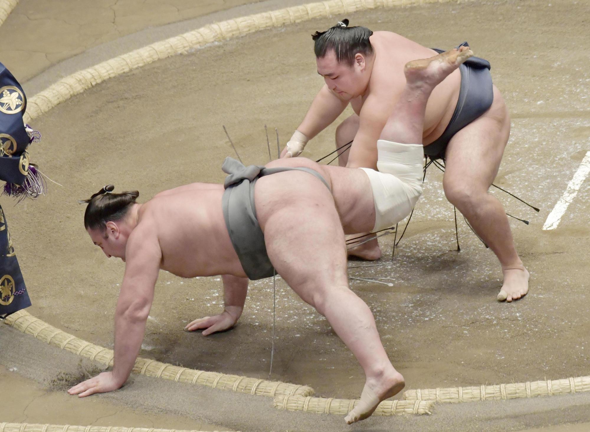 Kakuryu (top) takes down Tochinoshin on the first day of the New Year Grand Sumo Tournament on Sunday at Ryogoku Kokugikan. | KYODO