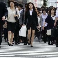 Pedestrians cross a road in Tokyo. Women hold just 3.4% of exec positions at listed Japan firms, far from 30% target: survey