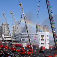 A man-made rainbow provides a colorful backdrop for the Tokyo Fire Department\'s annual New Year\'s firefighting skills ceremony Friday at the Tokyo Big Sight convention center in Koto Ward. | SATOKO KAWASAKI