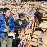 People who wrote their wishes on wooden ema plaques prepare to hang them up at Yushima Tenjin Shrine in Tokyo\'s Bunkyo Ward on Wednesday ahead of the entrance examination season. Yushima Tenjin is known as a shrine for scholars. | KYODO