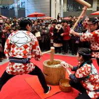 Staffers thump steamed rice into mochi during a New Year\'s event at the Tokyo International Forum in Chiyoda Ward on Tuesday. Mochi, a traditional rice cake, was served to visitors during the three-day event through Tuesday to celebrate the 20th anniversary of the venue\'s opening. | SATOKO KAWASAKI
