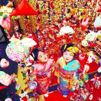 Girls in kimono admire ornaments displayed ahead of Girls\' Day, which falls on March 3, on Thursday at the Inatori hot springs resort in Higashiizu, Shizuoka Prefecture. | KYODO