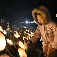 A girl lights a candle in a bamboo lantern during a ceremony Tuesday morning in Kobe marking the 22nd anniversary of the Great Hanshin Earthquake of Jan. 17, 1995. The quake killed more than 6,400 people. | KYODO