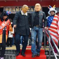 Men wearing masks of former U.S. President Barack Obama and new President Donald Trump walk down a red carpet in front of Usa Station in Oita Prefecture on Saturday. Residents decorated the station for Trump\'s inauguration because the name of their town is spelled the same as \"USA.\" | KYODO