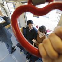 A heart-shaped strap hangs in a Keikyu Love Train in Yokohama on Tuesday ahead of Valentine\'s Day on Feb. 14. Keikyu Corp. began running the special train Tuesday on its Tokyo-area lines to \"help people who hold them find love.\" | KYODO