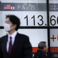 People walk past an electronic stock board on Friday. | AP