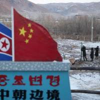 Chinese paramilitary policemen are seen building a fence near a marker depicting the North Korean and Chinese national flags with the words \"China North Korea Border\" at the border town of Tumen in China\'s Jilin province in December 2012. | AP