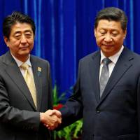 Chinese President Xi Jinping shakes hands with Prime Minister Shinzo Abe during their meeting at the Great Hall of the People, on the sidelines of Asia-Pacific Economic Cooperation meetings in Beijing in November 2014. Task force report highlights 'precarious' Sino-U.S. ties, urges visit to Japan, China to help repair relations