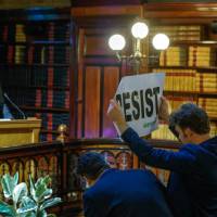 An environmental activist protests during a speech by Myron Ebell (left), who was appointed to lead U.S. President Donald Trump\'s Environmental Protection Agency\'s transition team, at the Solvay library in Brussels on Wednesday. | REUTERS