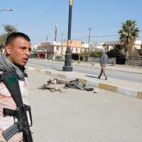An Iraqi soldier carries his weapon near corpses of Islamic State group militants killed in clashes in Mosul, Iraq, on Monday. | REUTERS