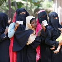 Rohingya women wait with vouchers to collect relief distributed by the Bangladesh Red Crescent Society at Kutupalang Unregistered Refugee Camp in Cox\'s Bazar, Bangladesh, Monday. | REUTERS