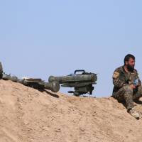 A Syrian Democratic Forces (SDF) fighter sits near an anti-tank missile in northern Deir al-Zor province ahead of an offensive against Islamic State militants Tuesday. | REUTERS