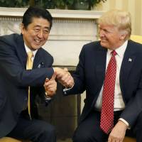 Prime Minister Shinzo Abe shakes hands with U.S. President Donald Trump during their meeting at the White House on Friday. | REUTERS