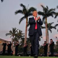 U.S. President Donald Trump arrives to a marching band at Trump International Golf Club in West Palm Beach, Florida, on Sunday. | REUTERS