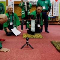 Members of the Bald Men Club take part in a unique game of tug-of-war by attaching suction pads onto their heads, at a hot springs facility in Tsuruta, Aomori Prefecture, Wednesday. | REUTERS