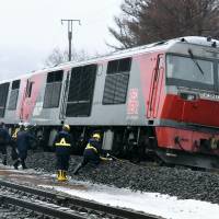 JR Hokkaido officials on Thursday inspect a freight train that derailed on the JR Muroran Main Line near the town of Toya. | KYODO