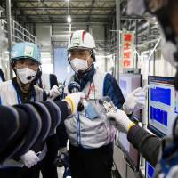 A Tokyo Electric employee leads a media tour Thursday at the crippled Fukushima No. 1 plant in Fukushima Prefecture. | AFP-JIJI