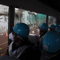 Journalists aboard a bus get a glimpse of the damaged No. 4 reactor building during a media tour Thursday at the Fukushima No. 1 plant. | AFP-JIJI