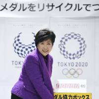 Tokyo Gov. Yuriko Koike drops a cell phone into the donation box for Olympic recycling drive at City Hall. | KYODO