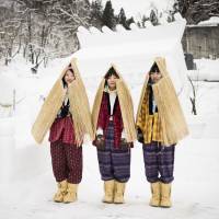 Women in traditional work pants stand in front of a shrine at the Inukko festival in Yuzawa in 2015. | JORDAN OXBOROUGH
