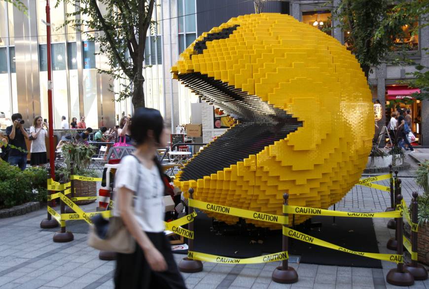 A woman walks past a giant Pac-Man in Tokyo's Shinjuku area installed in 2015 to promote the movie Tributes to the ‘father of Pac-Man’