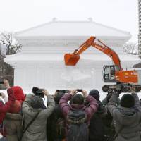 An excavator digs into a frozen sculpture Monday following the end of the annual Sapporo Snow Festival the previous day. This year\'s event drew a record high 2.6 million people and featured 200 sculptures made of snow and ice, including characters from \"Star Wars.\" | KYODO