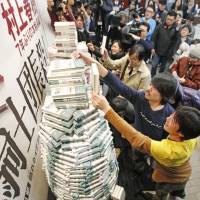 Fans reach up for copies of Haruki Murakami\'s latest book, \"Kishidancho Goroshi,\" during a sales campaign that kicked off at midnight Thursday at a Sanseido bookstore in Tokyo\'s Kanda district. | KYODO