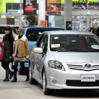 Visitors walk near a Toyota Motor Corp. Auris sedan displayed in the company\'s showroom in Tokyo on Feb. 8, 2011. The automaker is mulling future production of the new Auris in the U.K. | BLOOMBERG