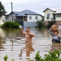 Residents of the New South Wales town of Lismore wade through floodwaters after heavy rains associated with Cyclone Debbie swelled rivers to record heights. Severe floods overwhelm Australian towns after cyclone