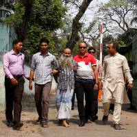 Security personnel bring Shaikh Mohammad Abul Kashem in front of media on Friday in Dhaka after his arrest on Thursday. | REUTERS