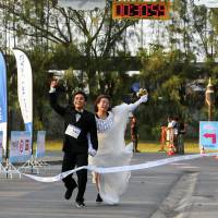 Sittichai Prasongsin, 27, and Sirada Thamwanna, 29, cross the finish line to win the \"Running of the Brides\" race at a park in Bangkok on Saturday. | REUTERS