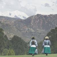 The snow-covered summit of Mount Illimani is seen from La Paz Golf Club in the Bolivian capital, with indigenous Aymara women in the foreground, in November 2008. As glaciers melt, project seeks to preserve ice cores showing climate history