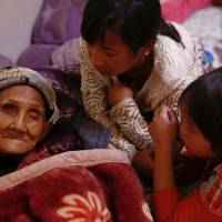 Refugees who fled fighting in neighboring Myanmar talk Saturday to a 96-year-old family member in the house of a relative in the village of Baiyan, near Nansan in Yunnan province, China. | REUTERS