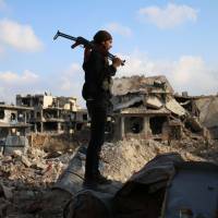 A rebel fighter stands amid the rubble of destroyed buildings in the rebel-held Syrian city of Daraa on March 14. | AFP-JIJI